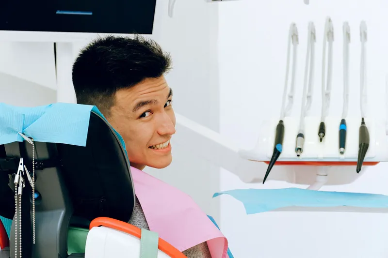 A smiling young man in a bright, modern dental chair