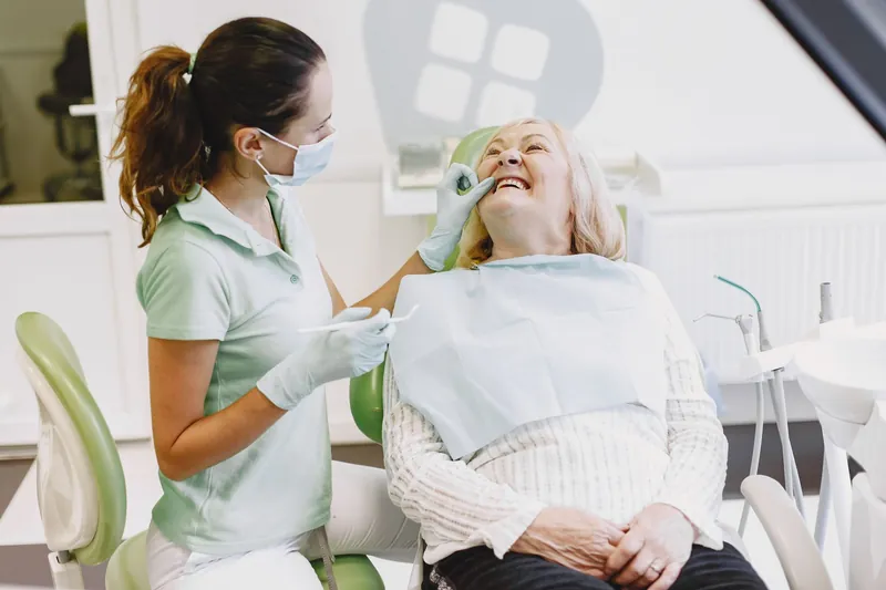 An older woman laughing in the dental chair with her dentist